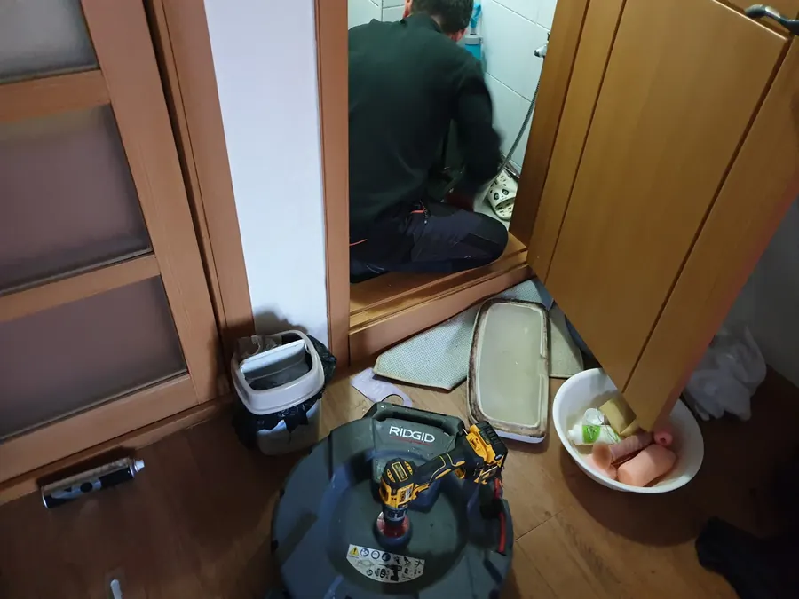 하부장 배관 연결부를 살펴보는 기술자의 손