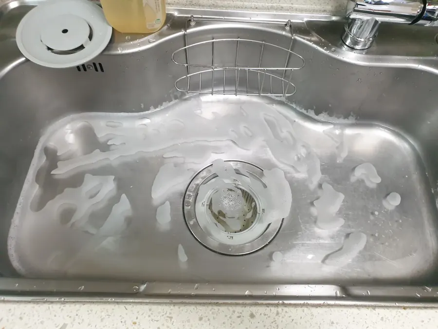 싱크대 배수구 거름망을 분리하고 내부를 확인하는 근접 사진